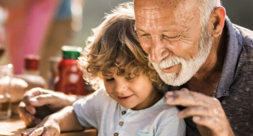 Mature man and his small grandchild enjoying on a picnic lunch with their dog.
