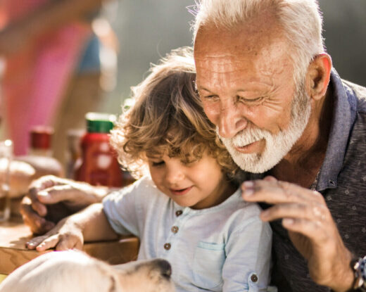 Mature man and his small grandchild enjoying on a picnic lunch with their dog.