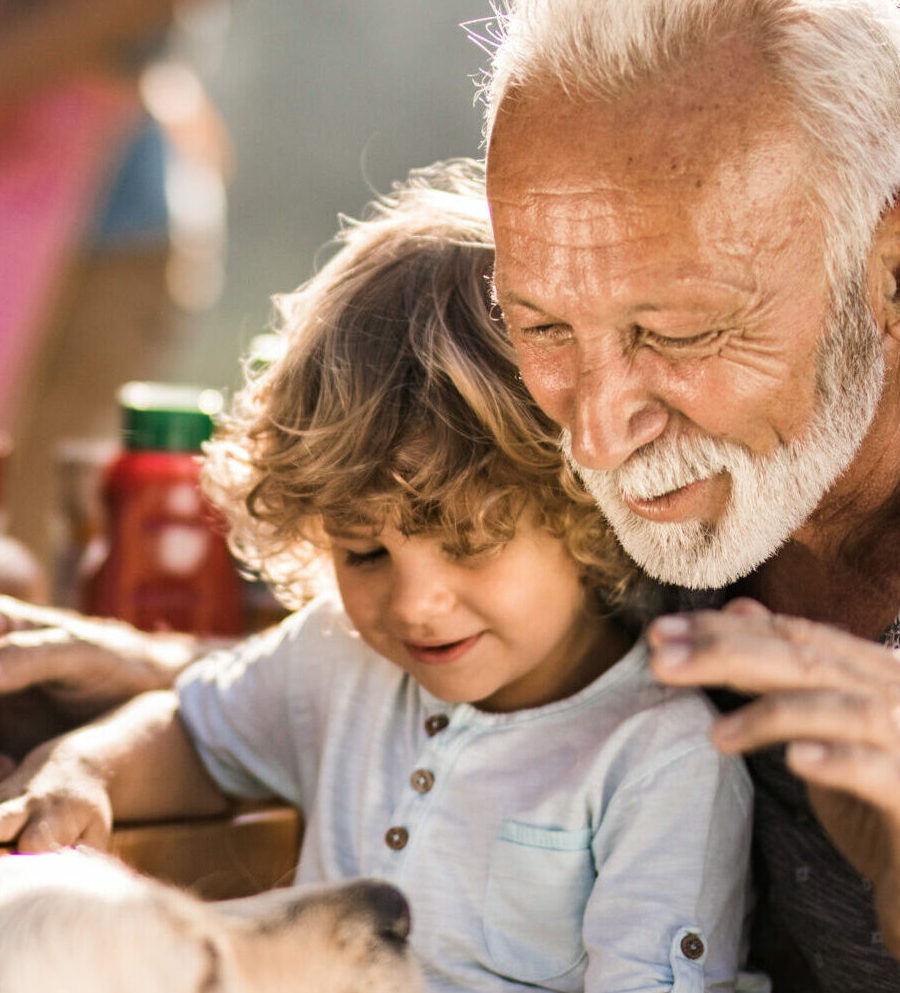 Mature man and his small grandchild enjoying on a picnic lunch with their dog.